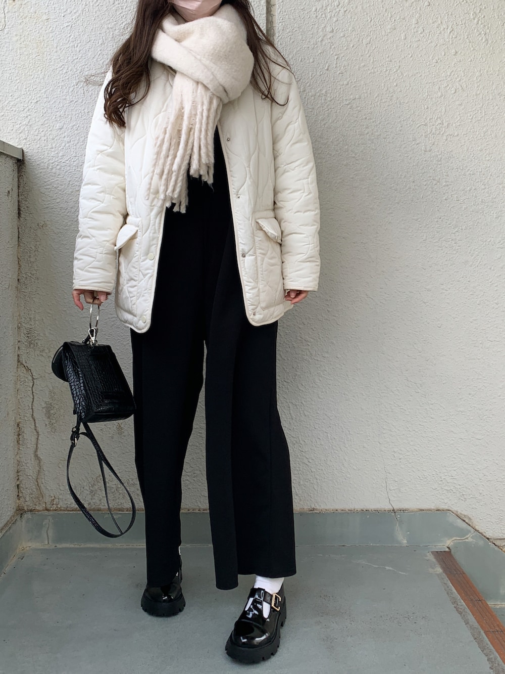 ブラック系のドレスシューズ、ホワイト系のノーカラーコート、ホワイト系のストール/ショールを着用したレディースの冬コーディネートの3枚目の写真