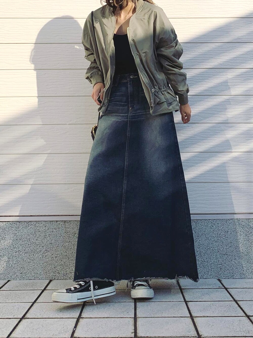 グリーン系のブルゾン、ブルー系のデニムスカート、ブラック系のスニーカーを着用したレディースの冬コーディネートの2枚目の写真