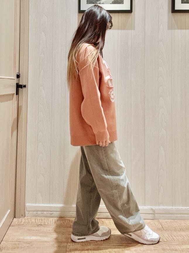 オレンジ系のニット/セーター、グレー系のデニムパンツを着用したレディースの冬コーディネートの2枚目の写真