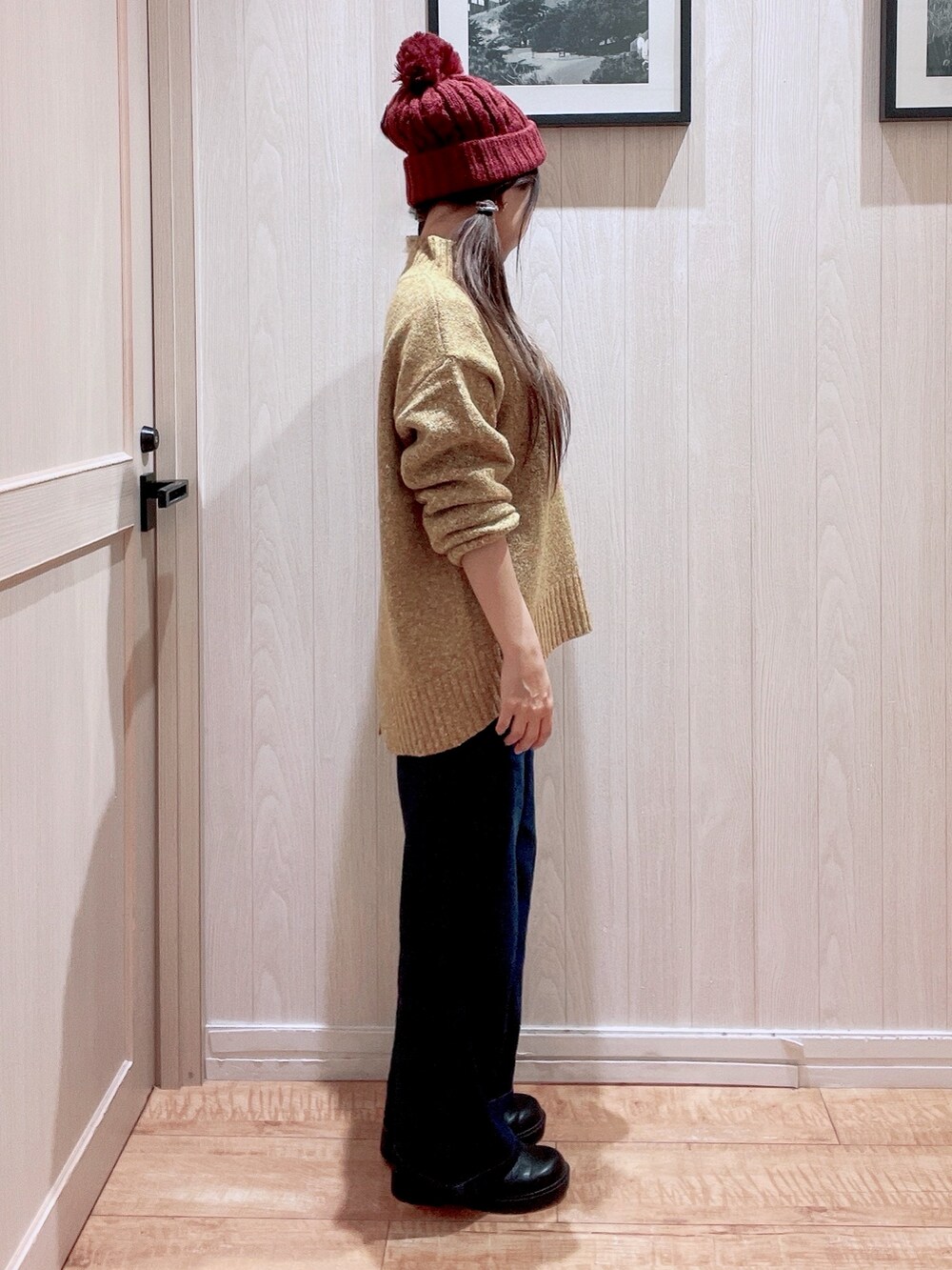 イエロー系のニット/セーター、ブラック系のブーツ、ブルー系のデニムパンツを着用したレディースの秋コーディネートの2枚目の写真