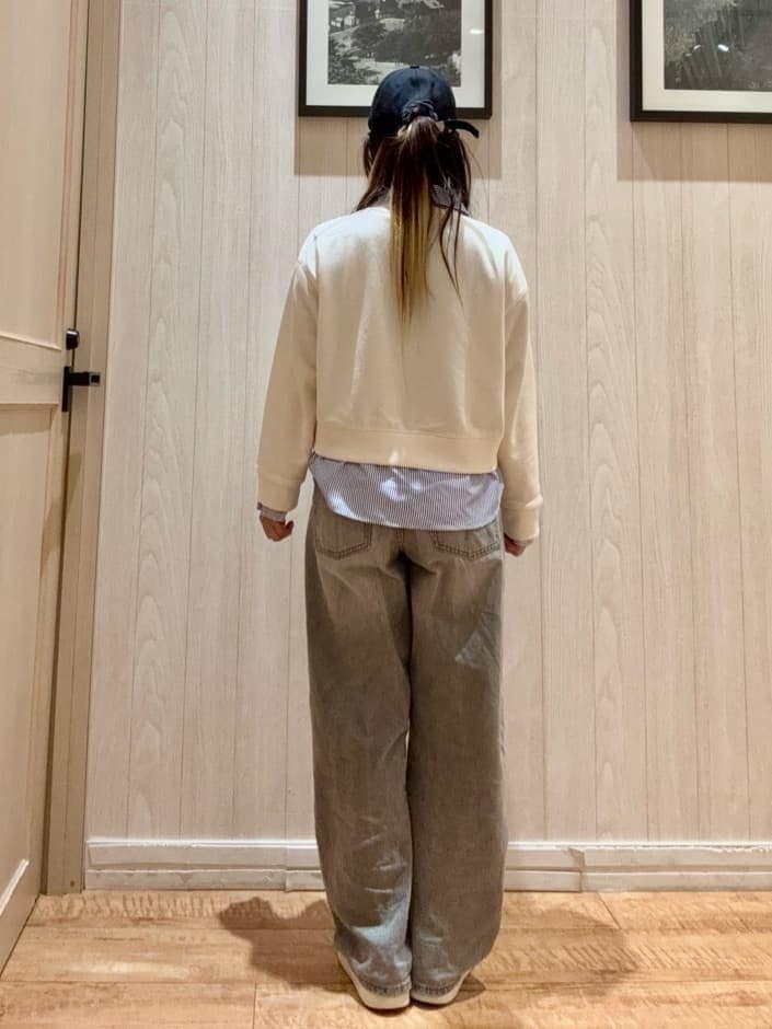 グレー系のデニムパンツ、ホワイト系のスウェット、シルバー系のスニーカーを着用したレディースの春コーディネートの3枚目の写真
