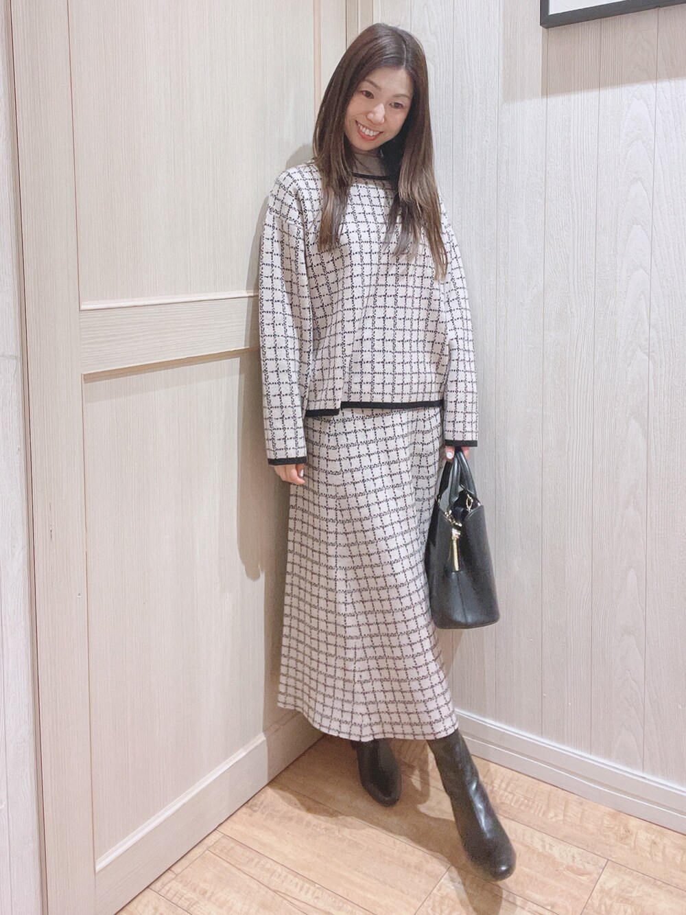 ベージュ系のニット/セーター、ベージュ系のスカート、ブラック系のトートバッグを着用したレディースの冬コーディネートの2枚目の写真