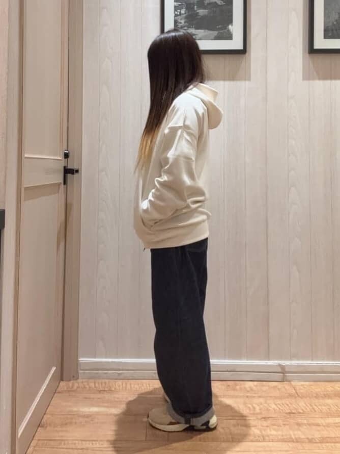 ホワイト系のパーカー、ブルー系のデニムパンツを着用したレディースの冬コーディネートの3枚目の写真