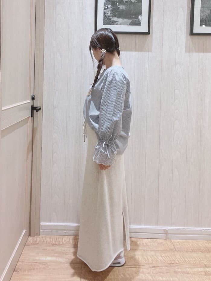 ブルー系のシャツ/ブラウス、グレー系のスカート、ブラック系のトートバッグを着用したレディースの春コーディネートの2枚目の写真