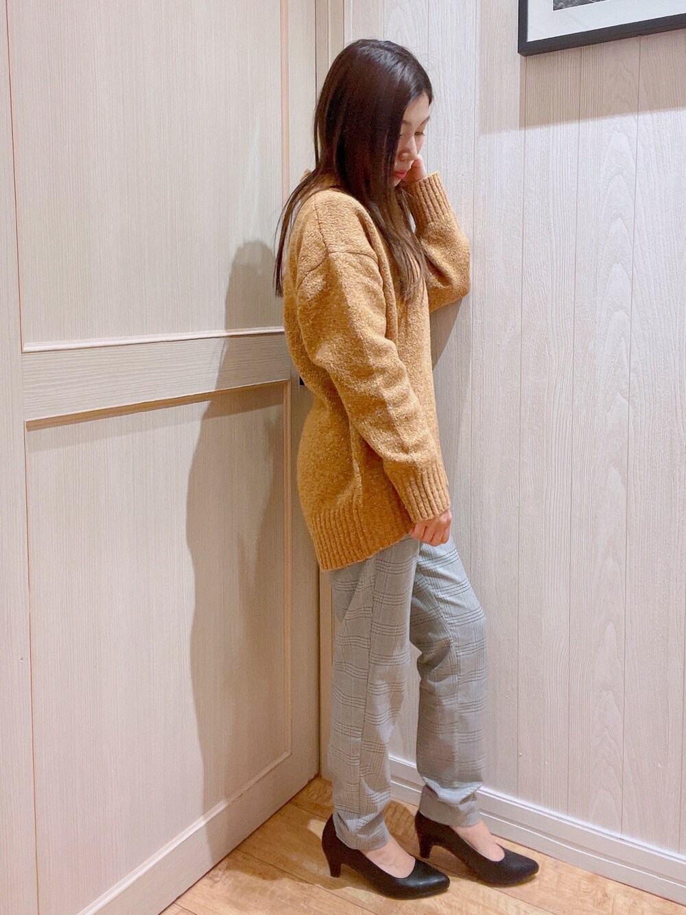 オレンジ系のニット/セーター、グレー系のその他パンツ、ブラック系のパンプスを着用したレディースの冬コーディネートの2枚目の写真