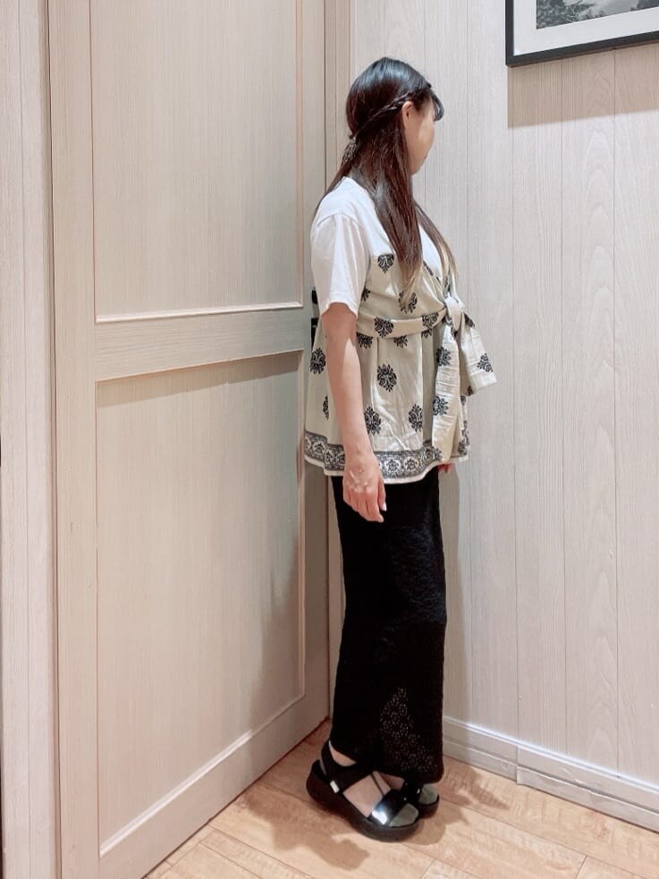ベージュ系のTシャツ/カットソー、ブラック系のスカート、ブラック系のサンダルを着用したレディースの夏コーディネートの2枚目の写真