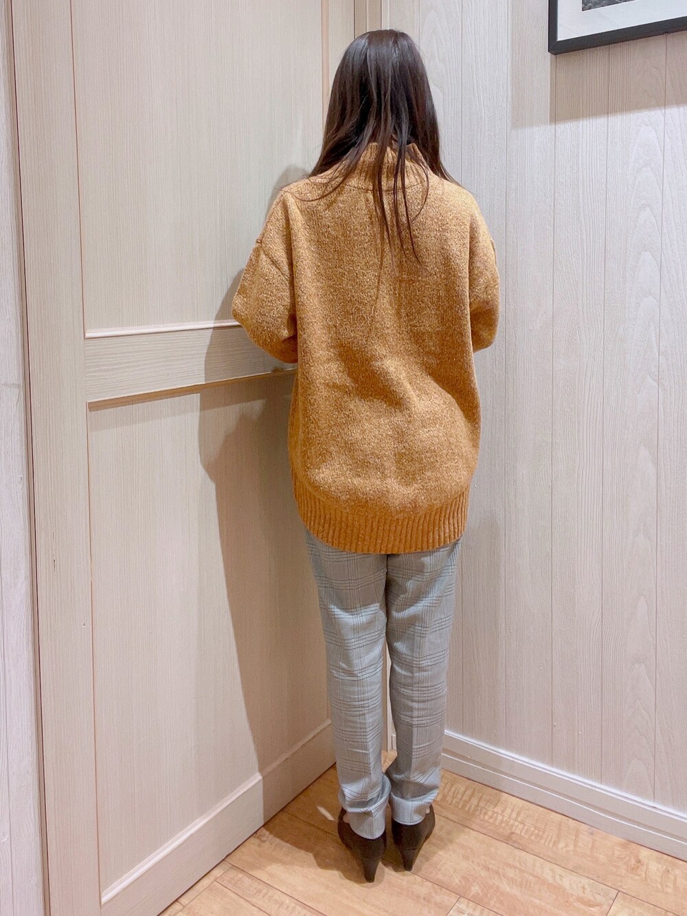 オレンジ系のニット/セーター、グレー系のその他パンツ、ブラック系のパンプスを着用したレディースの冬コーディネートの3枚目の写真