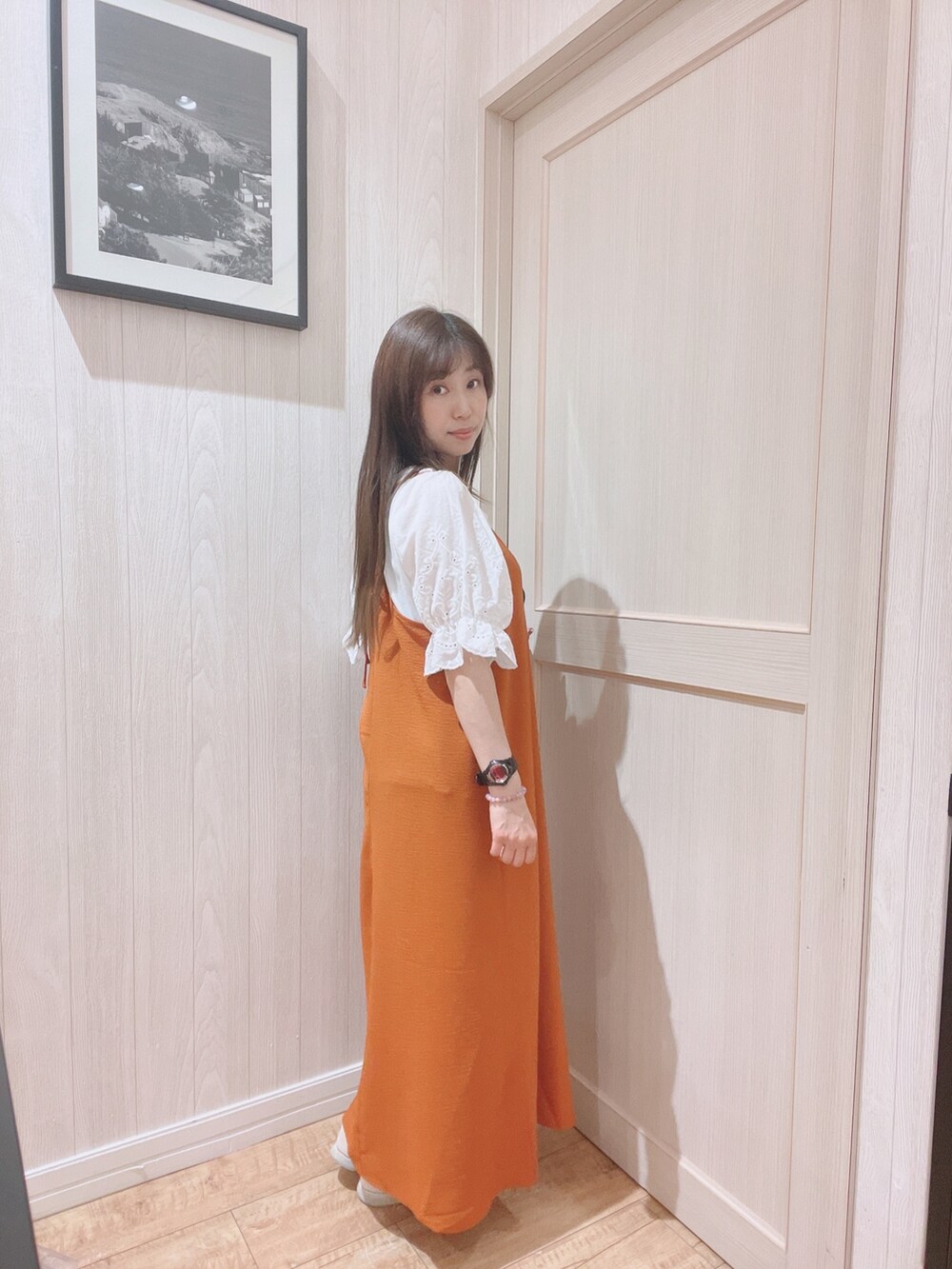 オレンジ系のワンピース、ホワイト系のTシャツ/カットソーを着用したレディースの春コーディネートの2枚目の写真