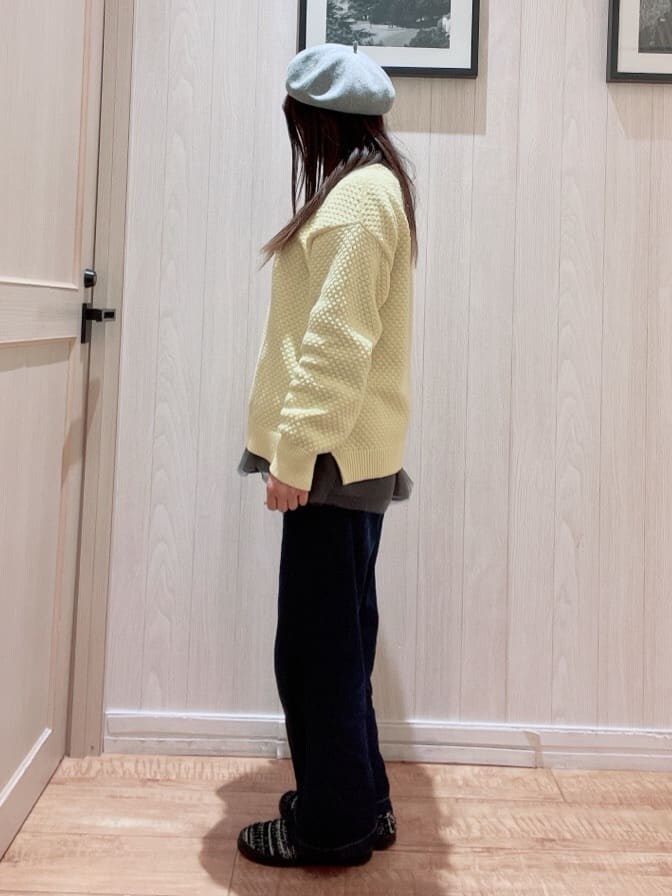 イエロー系のニット/セーター、グレー系のTシャツ/カットソー、ブラック系のショルダーバッグを着用したレディースの冬コーディネートの2枚目の写真