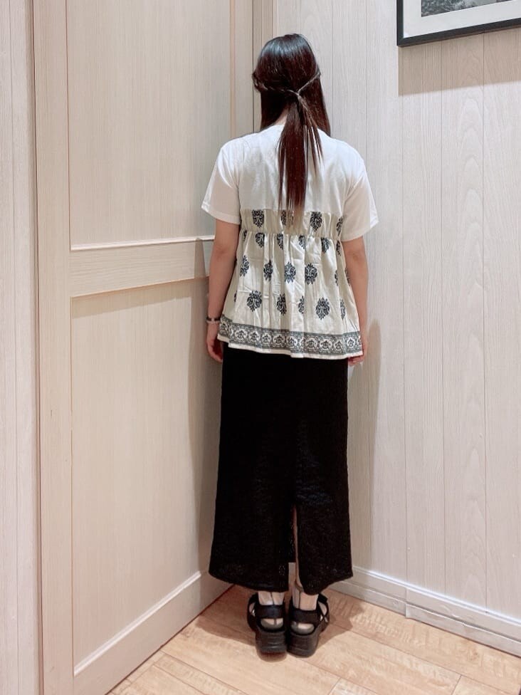 ベージュ系のTシャツ/カットソー、ブラック系のスカート、ブラック系のサンダルを着用したレディースの夏コーディネートの3枚目の写真