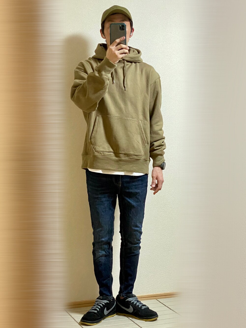 ブラック系のスニーカー、ブルー系のデニムパンツ、グリーン系のパーカーを着用したメンズの秋コーディネートの4枚目の写真