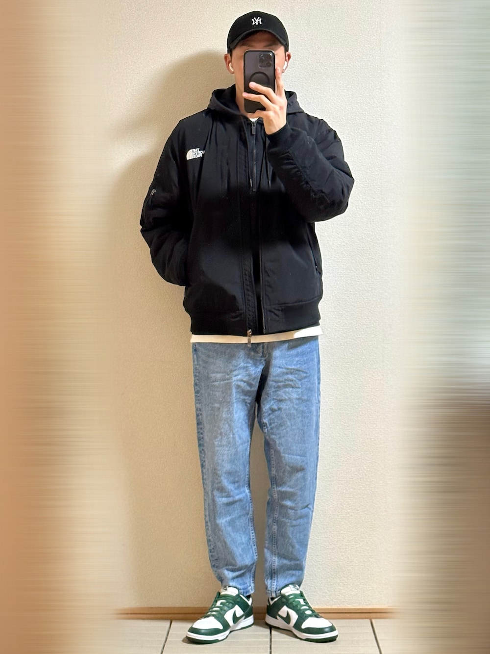 グリーン系のスニーカー、ブルー系のデニムパンツ、ブラック系のブルゾンを着用したメンズの冬コーディネートの2枚目の写真