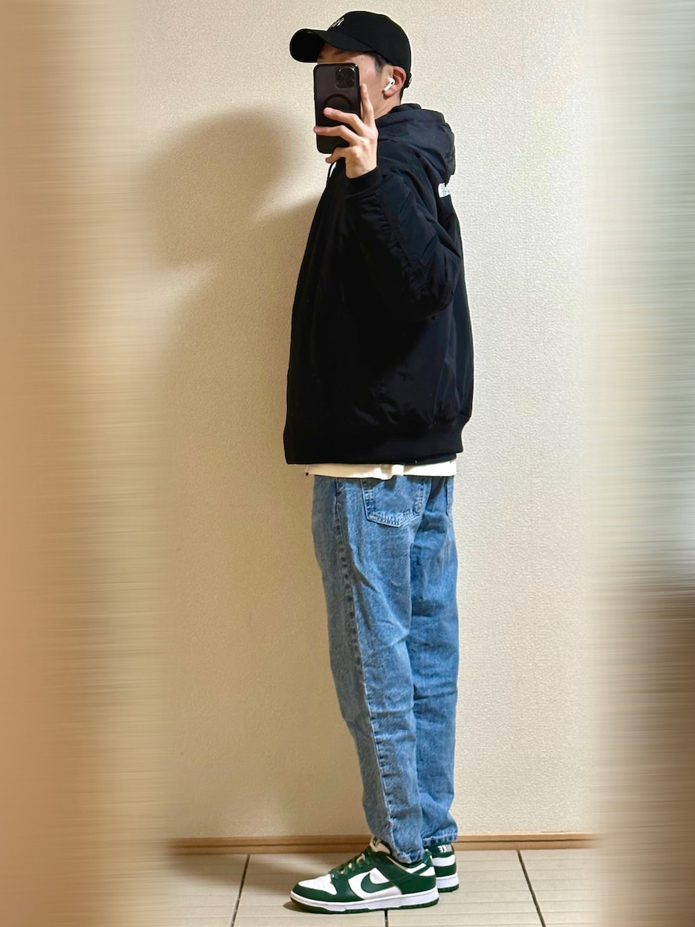 グリーン系のスニーカー、ブルー系のデニムパンツ、ブラック系のブルゾンを着用したメンズの冬コーディネートの4枚目の写真