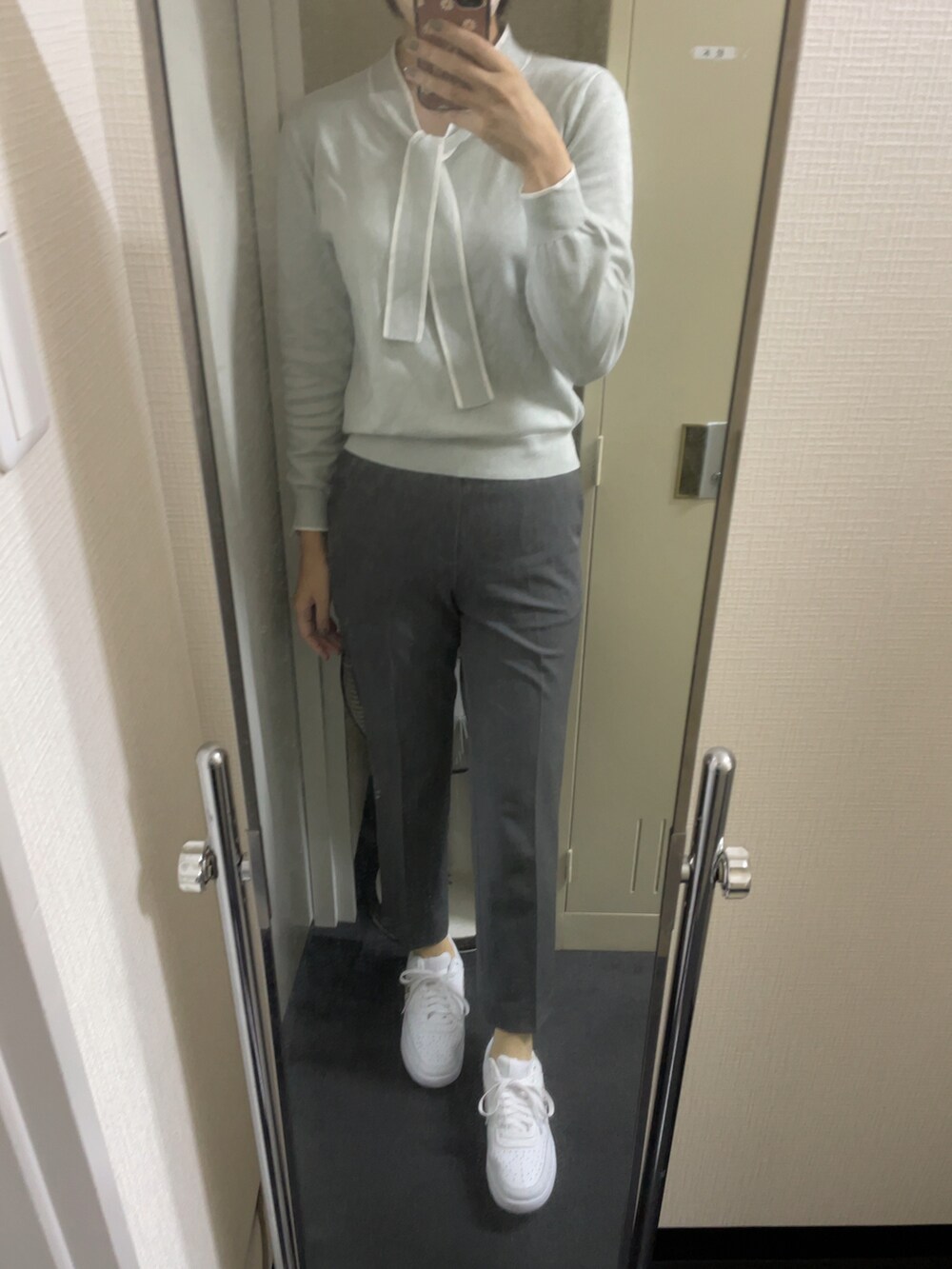 ベージュ系のステンカラーコート、グレー系のパンツ、ホワイト系のスニーカーを着用したレディースの春コーディネートの2枚目の写真