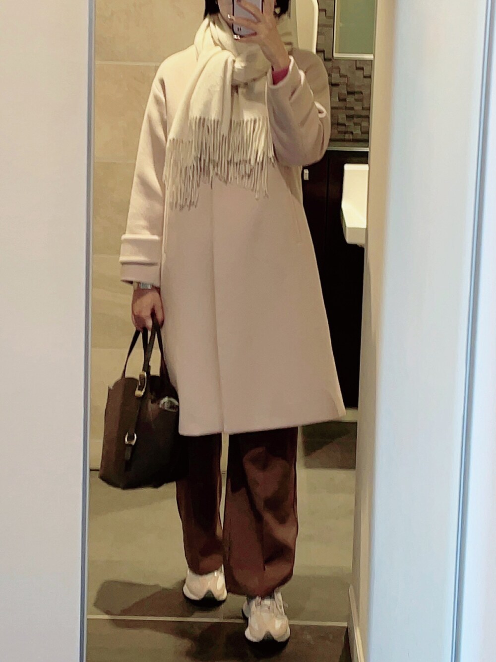 ピンク系のニット/セーター、ブラウン系のスラックス、ベージュ系のスニーカーを着用したレディースの冬コーディネートの2枚目の写真