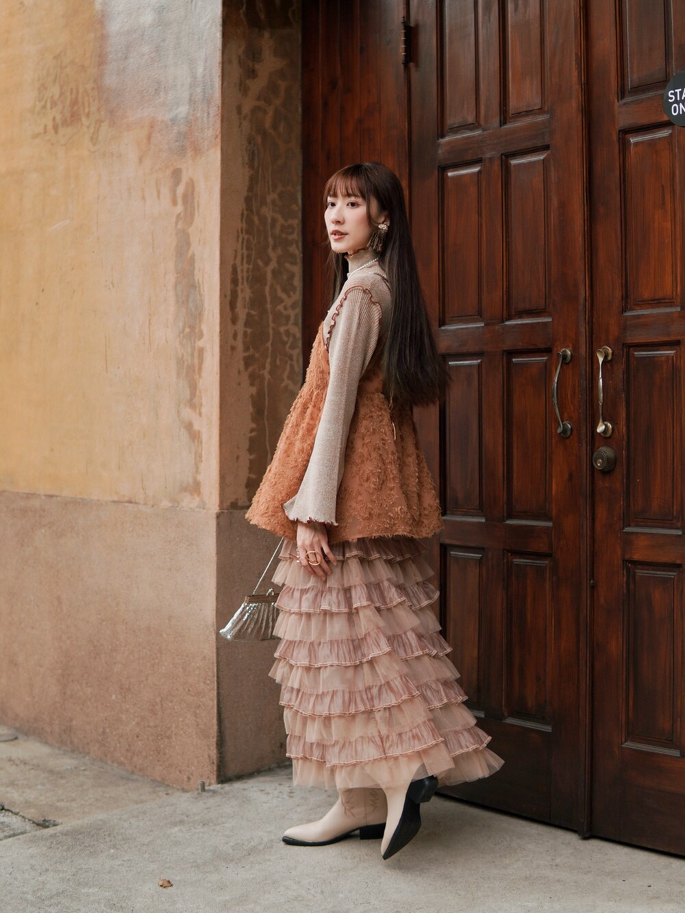 ホワイト系のシューズ、オレンジ系のトップス、ベージュ系のトップスを着用したレディースの冬コーディネートの2枚目の写真