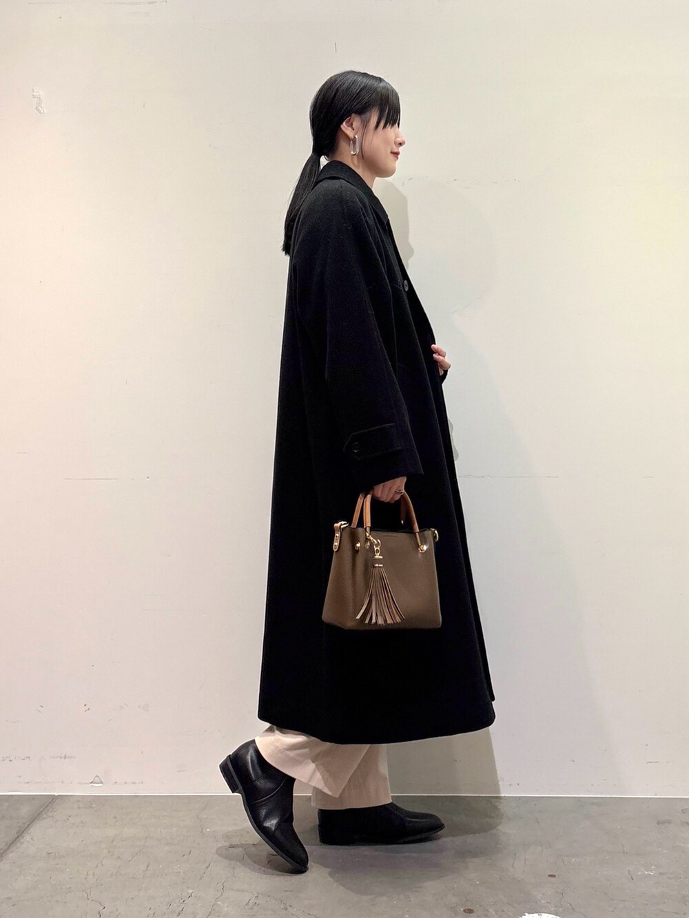 ブラック系のその他アウター、ベージュ系のニット/セーター、ホワイト系のその他パンツを着用したレディースの冬コーディネートの2枚目の写真