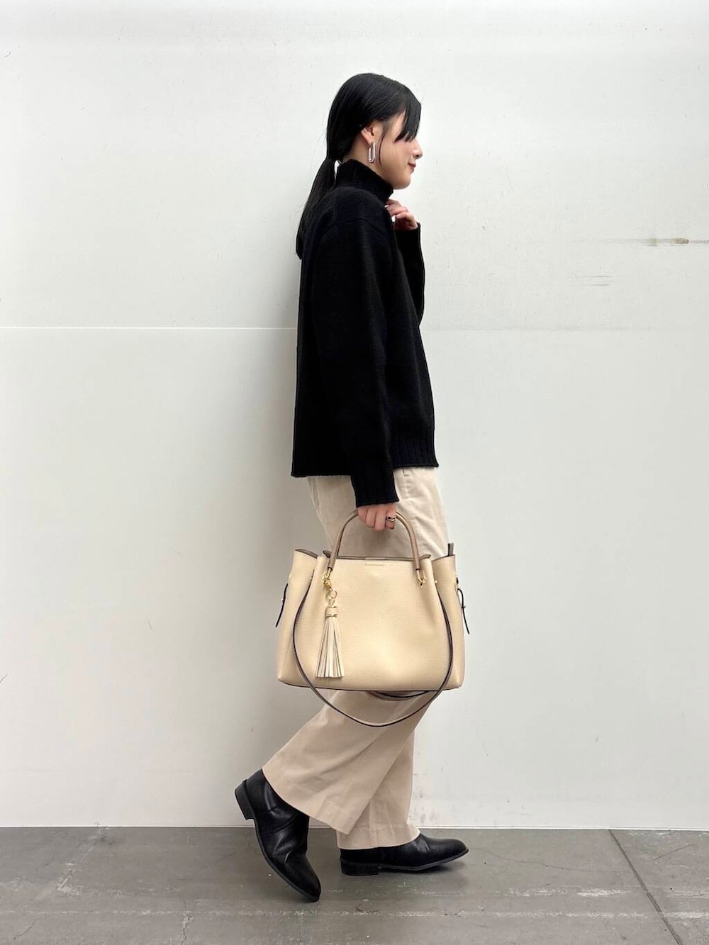 ホワイト系のトートバッグ、ブラック系のブーツ、ホワイト系のその他パンツを着用したレディースの冬コーディネートの2枚目の写真