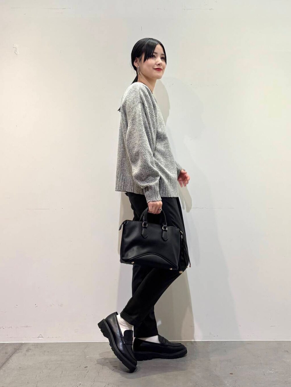 グレー系のニット/セーター、ブラック系のボストンバッグ、グレー系のその他パンツを着用したレディースの冬コーディネートの2枚目の写真