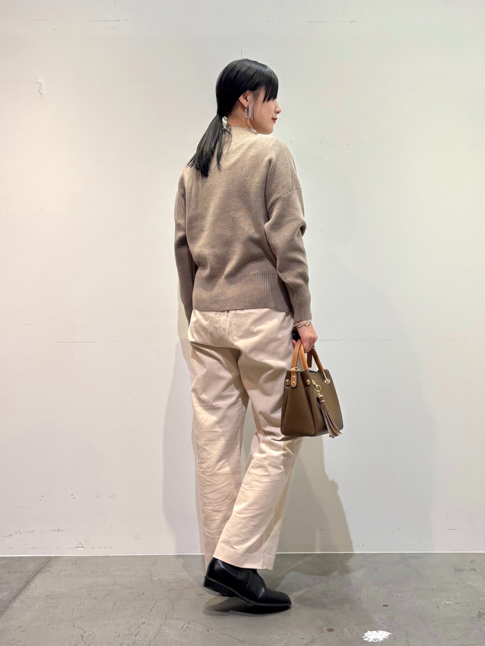 ブラック系のその他アウター、ベージュ系のニット/セーター、ホワイト系のその他パンツを着用したレディースの冬コーディネートの6枚目の写真