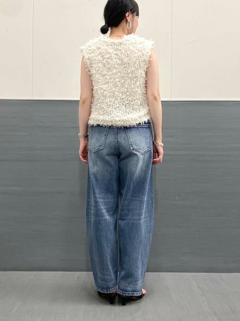 ブルー系のデニムパンツ、ホワイト系のベスト、ブラック系のサンダルを着用したレディースの夏コーディネートの8枚目の写真