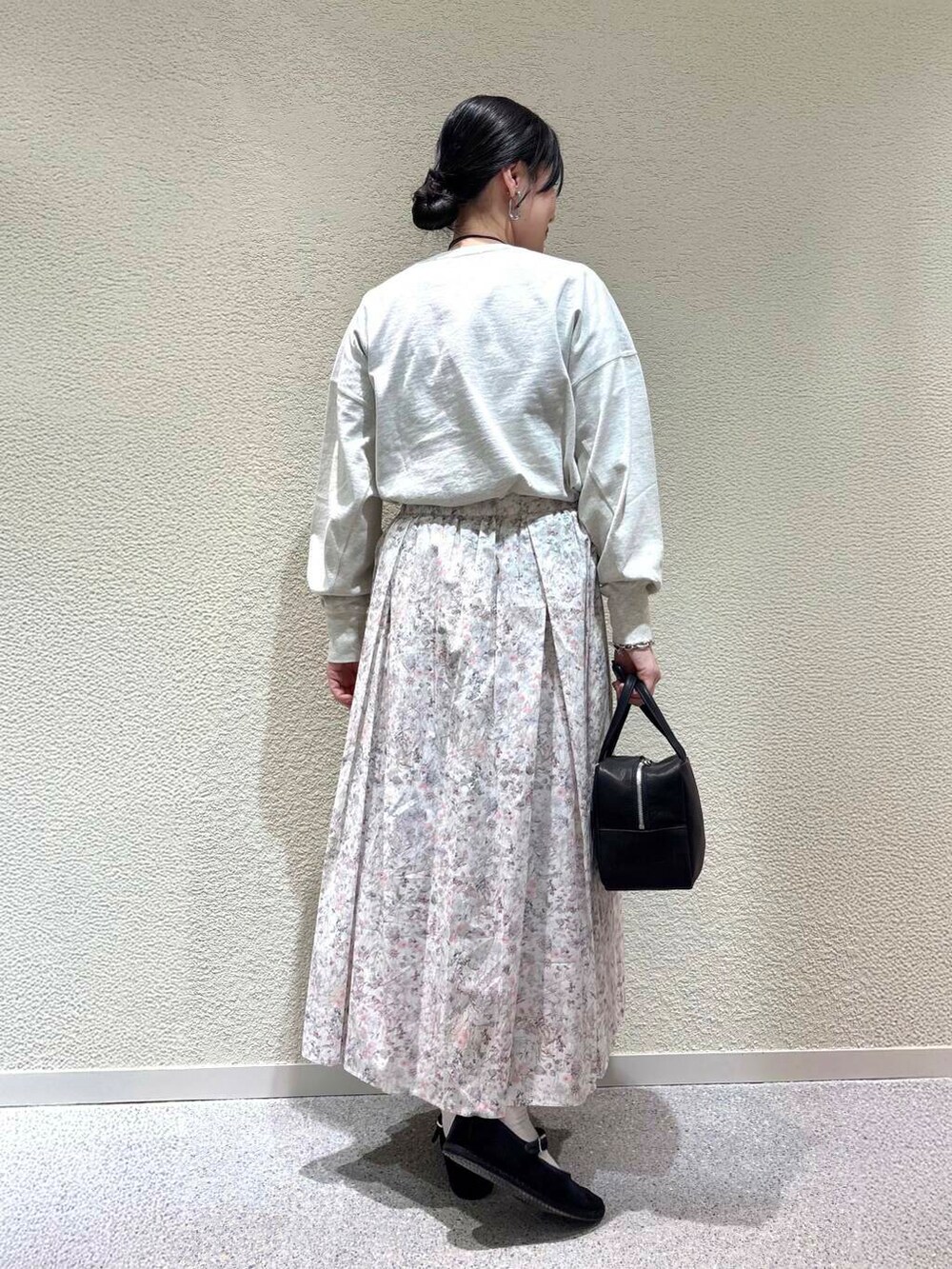 ベージュ系のTシャツ/カットソー、ホワイト系のスカート、ホワイト系のダウンジャケット/コートを着用したレディースの春コーディネートの6枚目の写真