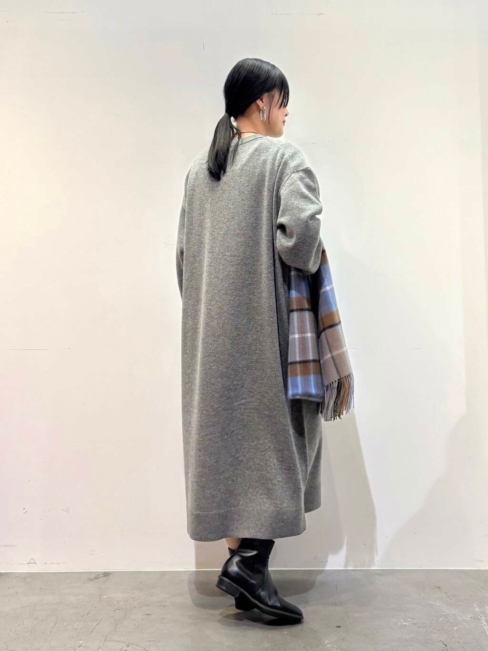 ブラック系のダウンジャケット/コート、ブラック系のブーツ、グレー系のワンピースを着用したレディースの冬コーディネートの6枚目の写真