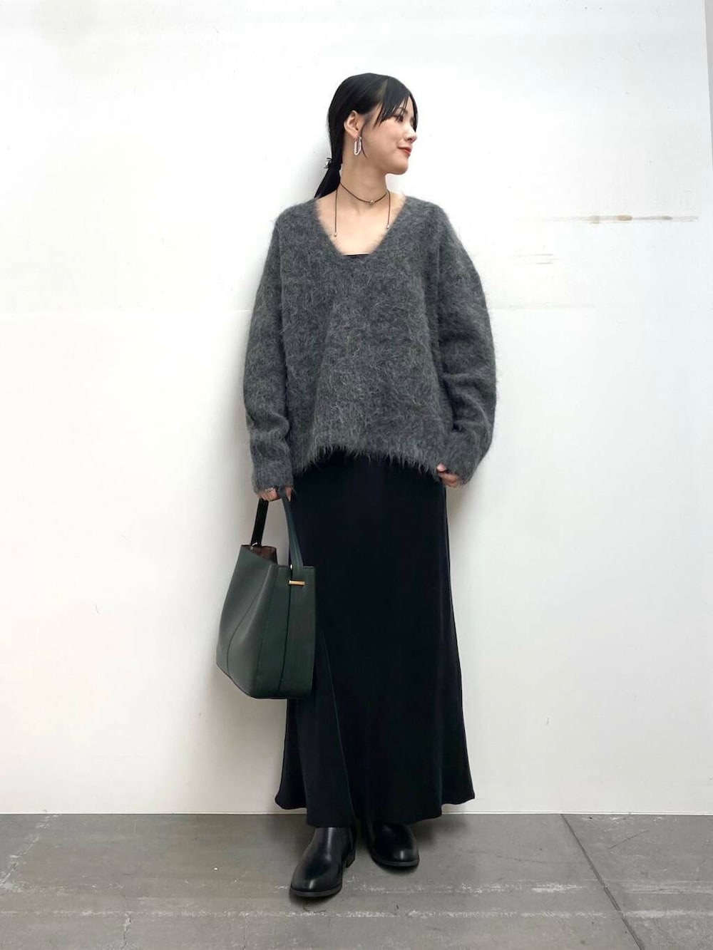 グリーン系のハンドバッグ、ブラック系のブーツ、ブラック系のスカートを着用したレディースの冬コーディネートの3枚目の写真