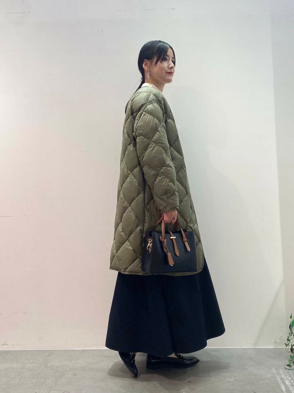 ブラック系のハンドバッグ、グリーン系のダウンジャケット/コート、ブラック系のローファーを着用したレディースの秋コーディネートの2枚目の写真
