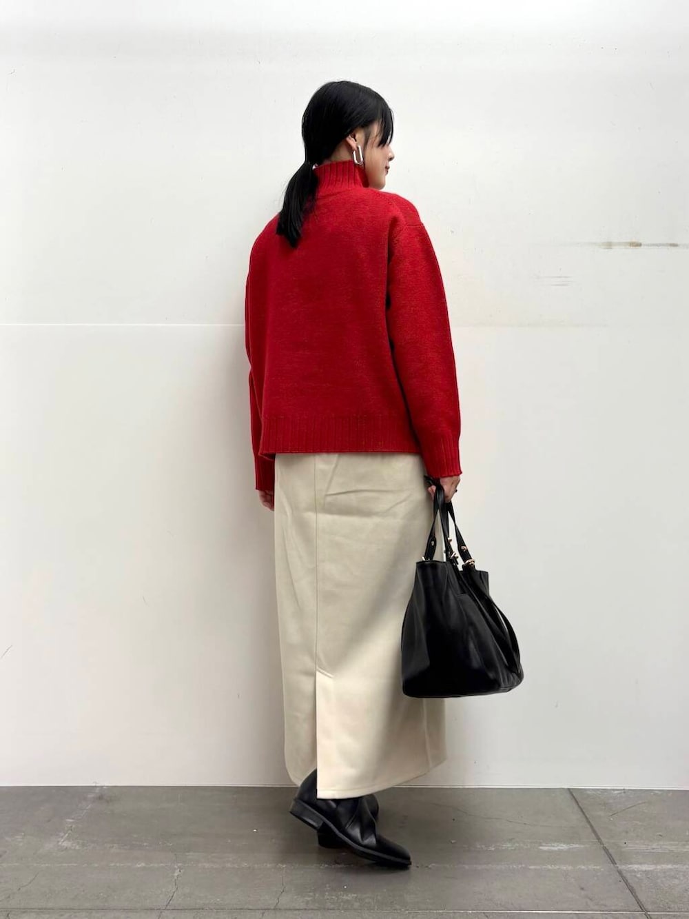 ブラック系のトートバッグ、ブラック系のブーツ、ホワイト系のスカートを着用したレディースの冬コーディネートの3枚目の写真