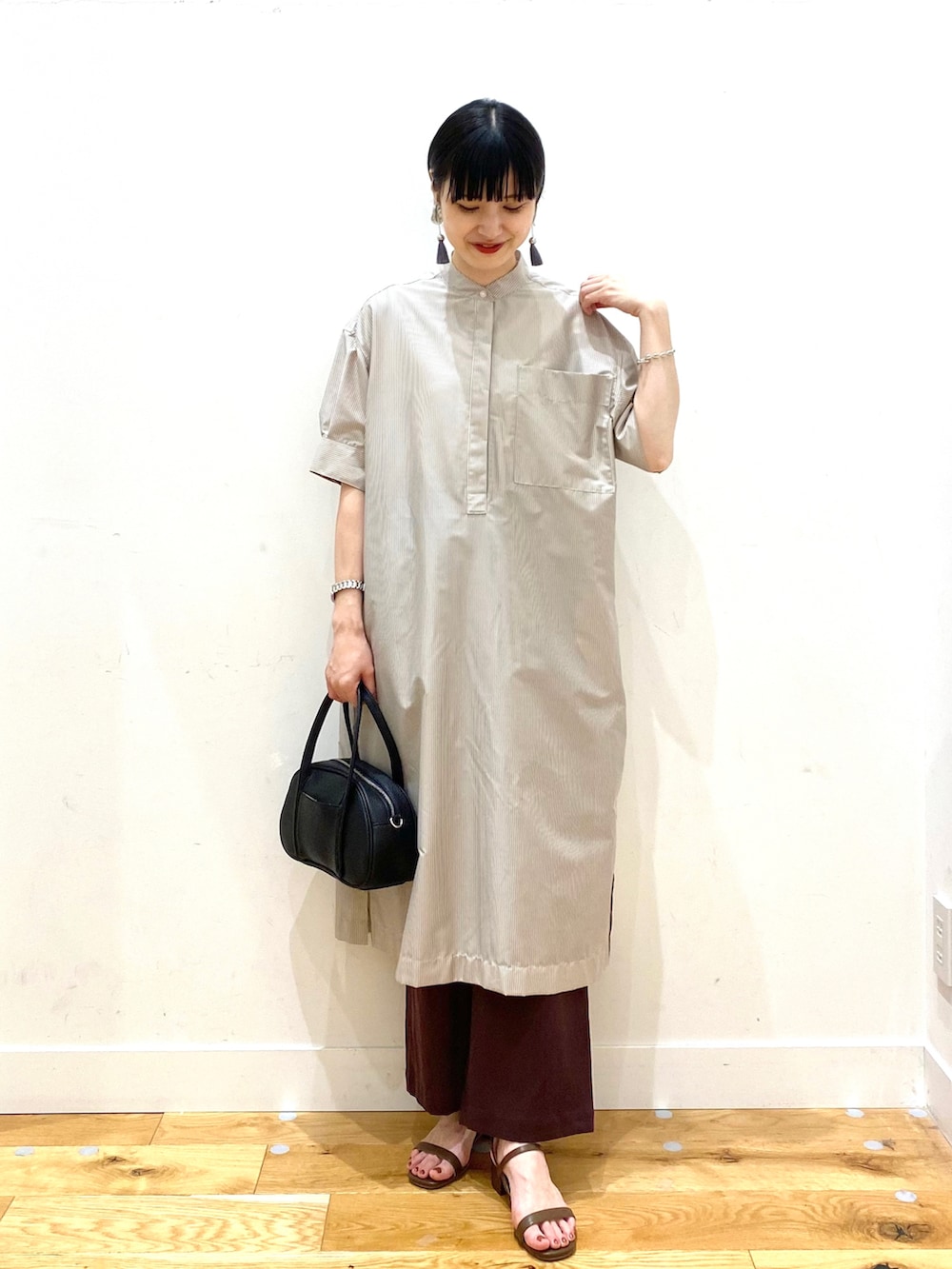 ベージュ系のワンピース、レッド系のその他パンツ、ブラック系のショルダーバッグを着用したレディースの春コーディネートの2枚目の写真