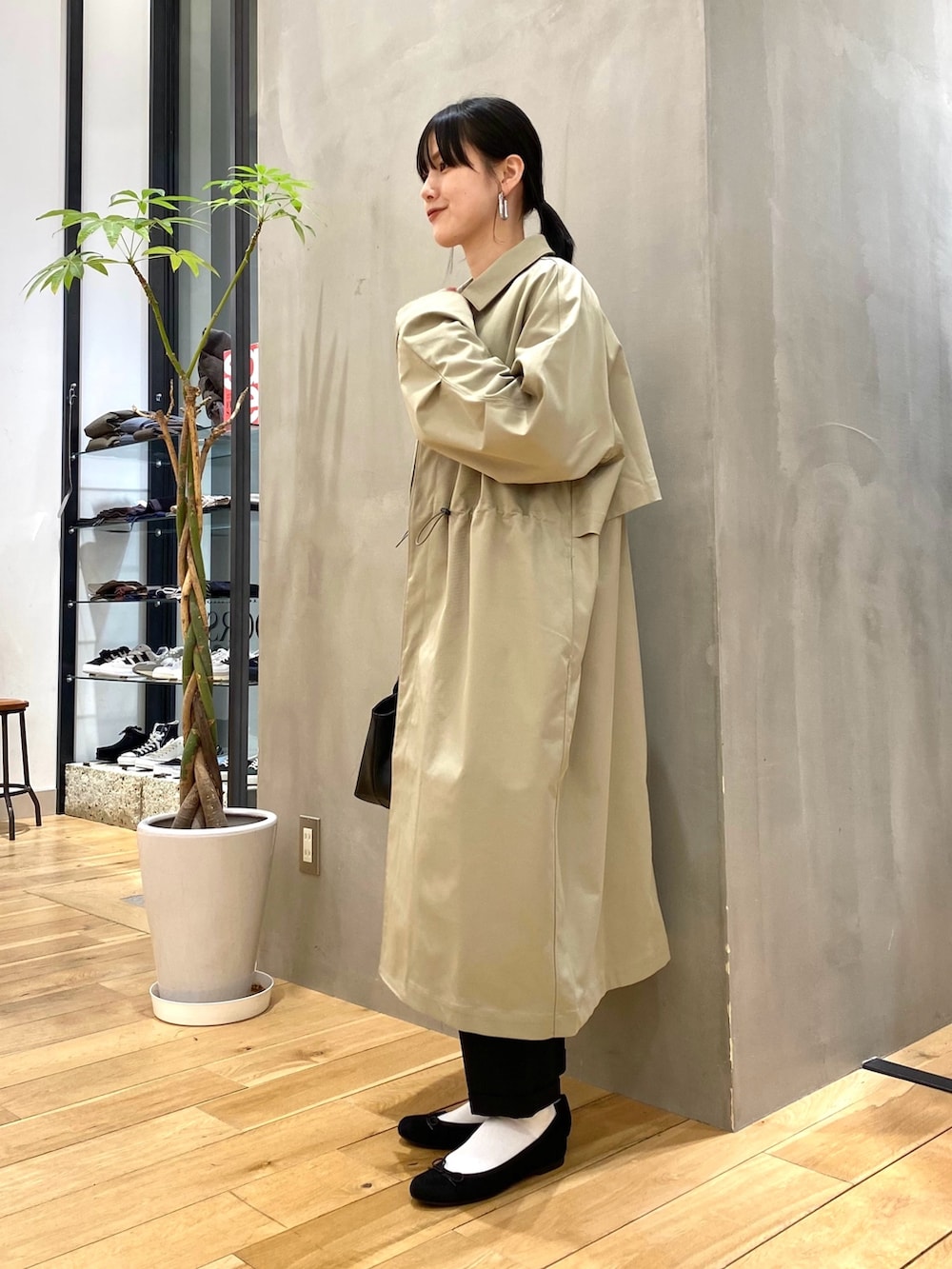 グリーン系のステンカラーコート、ホワイト系のニット/セーター、ブラック系のその他パンツを着用したレディースの冬コーディネートの2枚目の写真