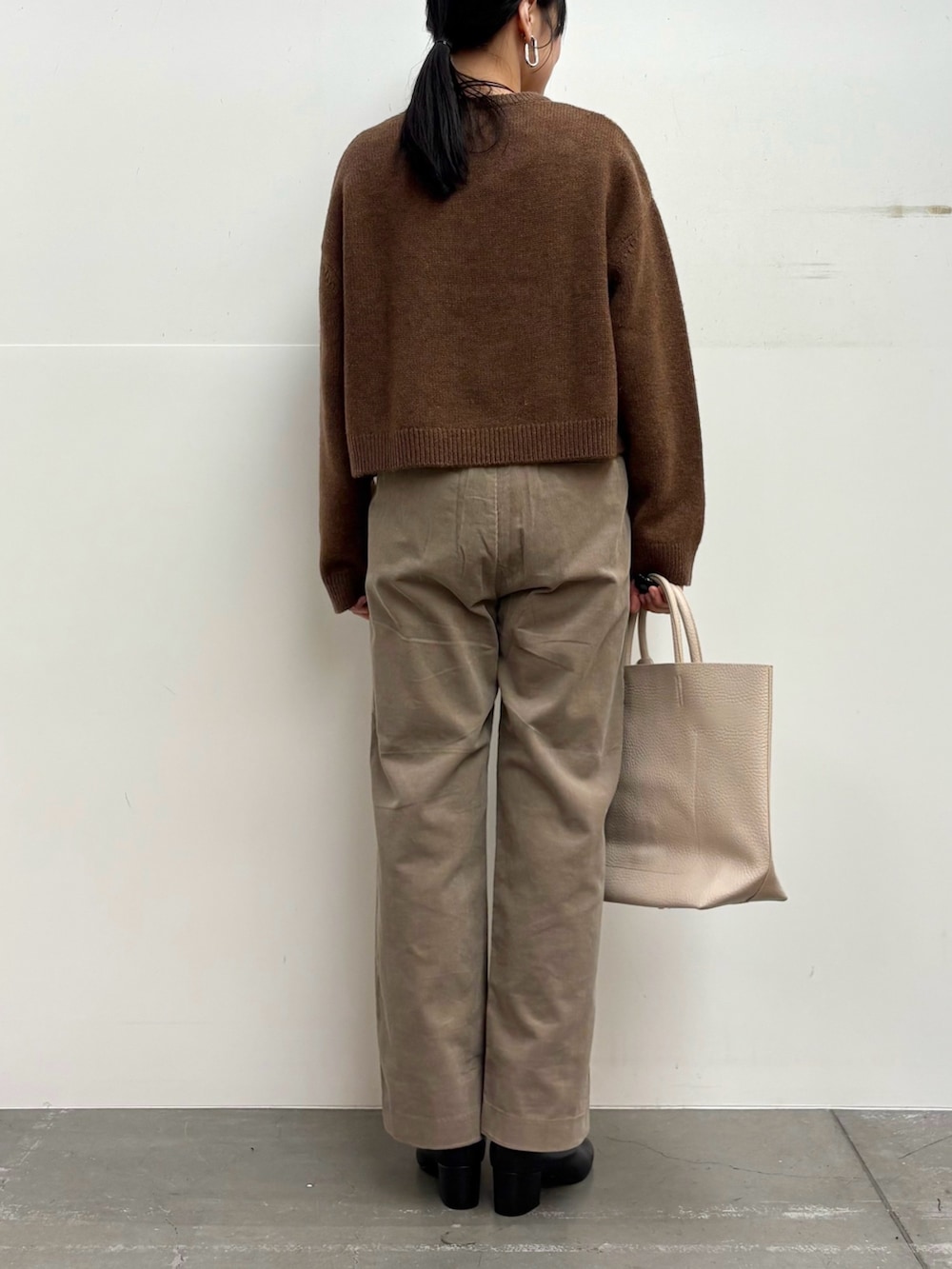 ブラウン系のニット/セーター、ベージュ系のその他パンツ、ホワイト系のトートバッグを着用したレディースの冬コーディネートの5枚目の写真