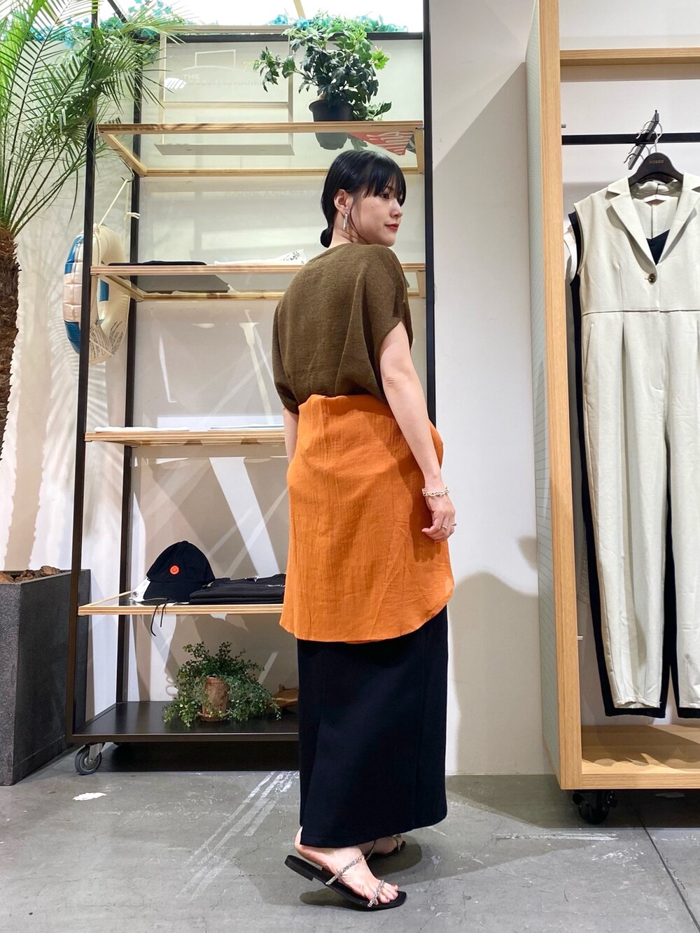 ブラウン系のニット/セーター、オレンジ系のシャツ/ブラウス、ブラック系のスカートを着用したレディースの夏コーディネートの5枚目の写真