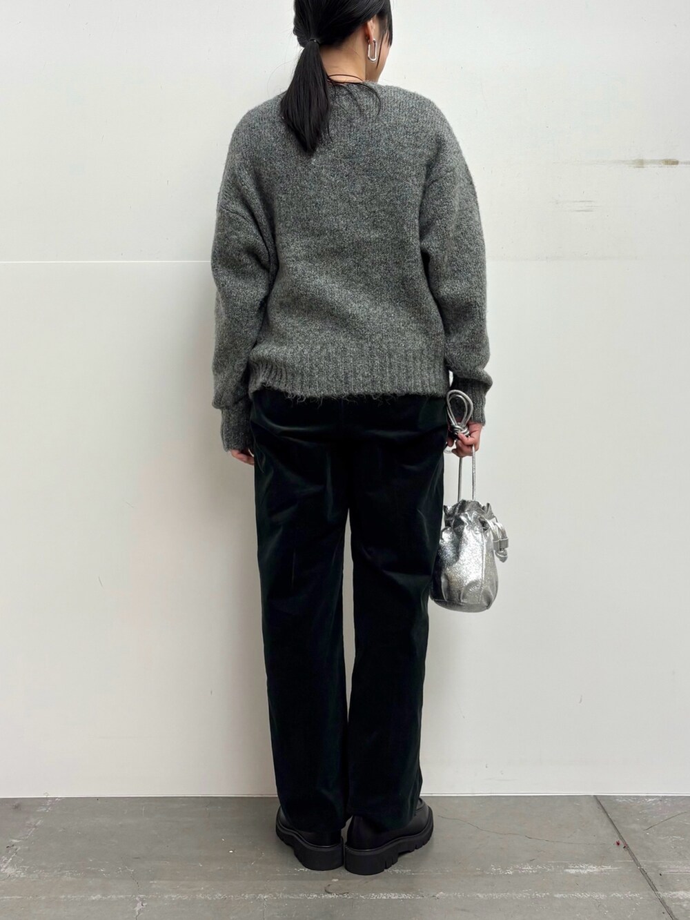 グレー系のニット/セーター、ブラック系のその他パンツ、シルバー系のショルダーバッグを着用したレディースの冬コーディネートの6枚目の写真