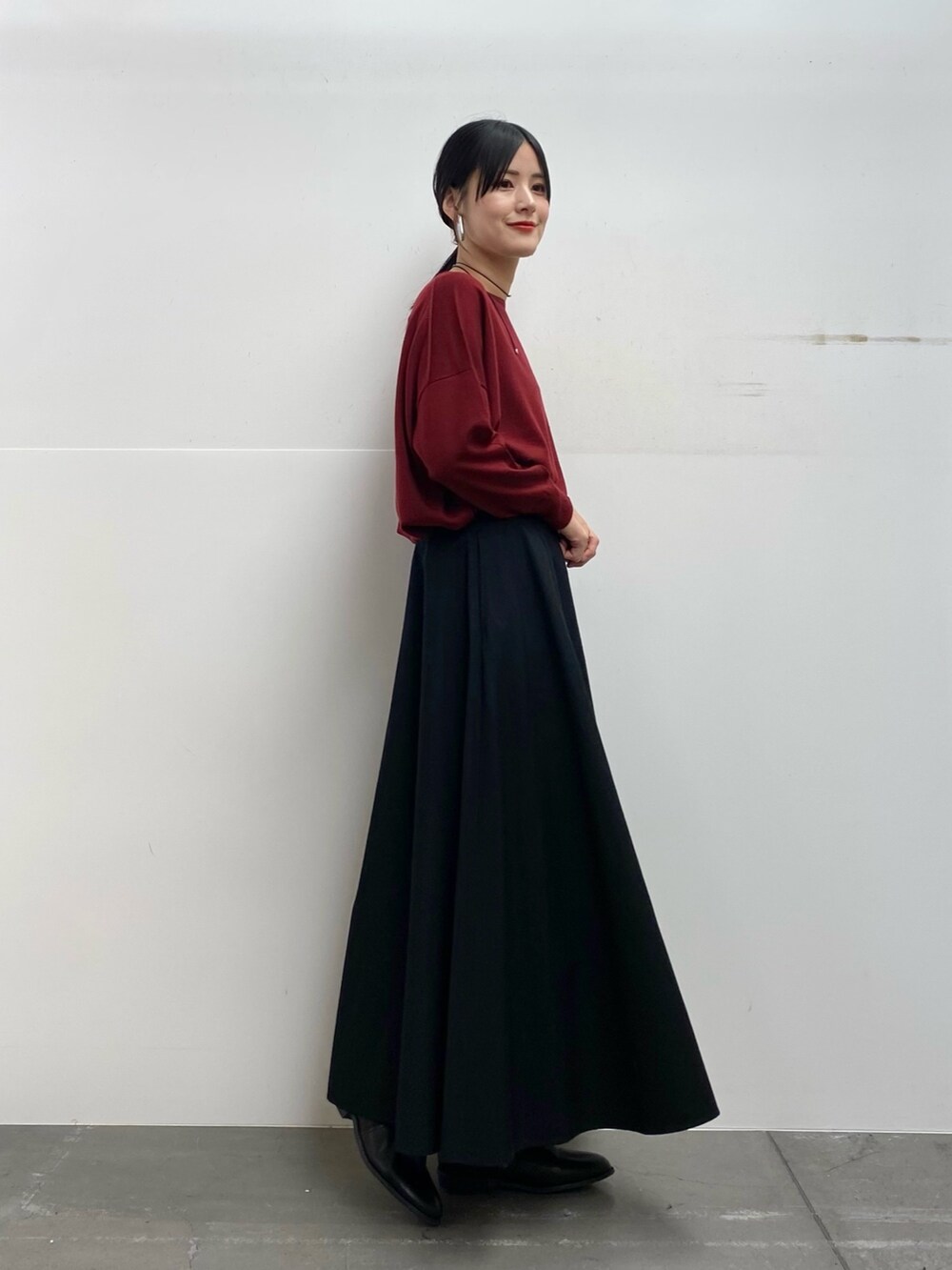 グレー系のステンカラーコート、レッド系のニット/セーター、ブラック系のスカートを着用したレディースの秋コーディネートの5枚目の写真