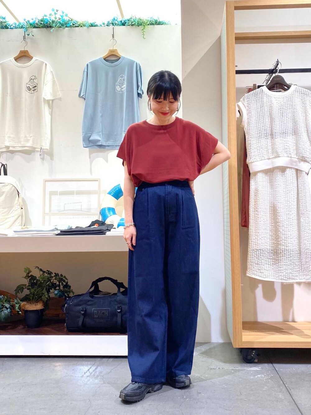 レッド系のニット/セーター、ブルー系のデニムパンツを着用したレディースの夏コーディネートの2枚目の写真