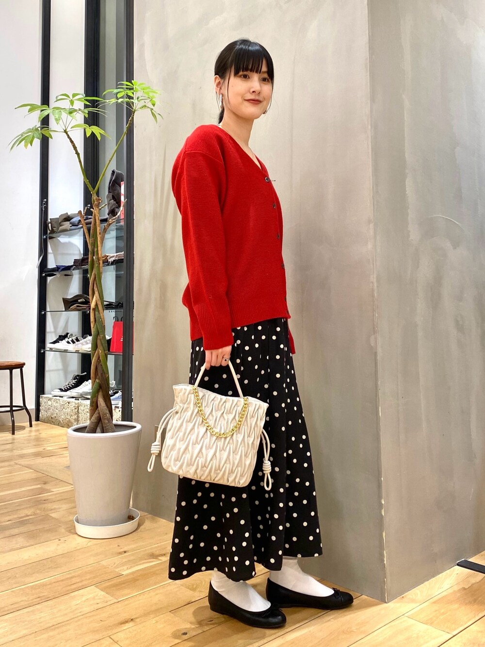 レッド系のカーディガン/ボレロ、ブラック系のスカートを着用したレディースの冬コーディネートの2枚目の写真