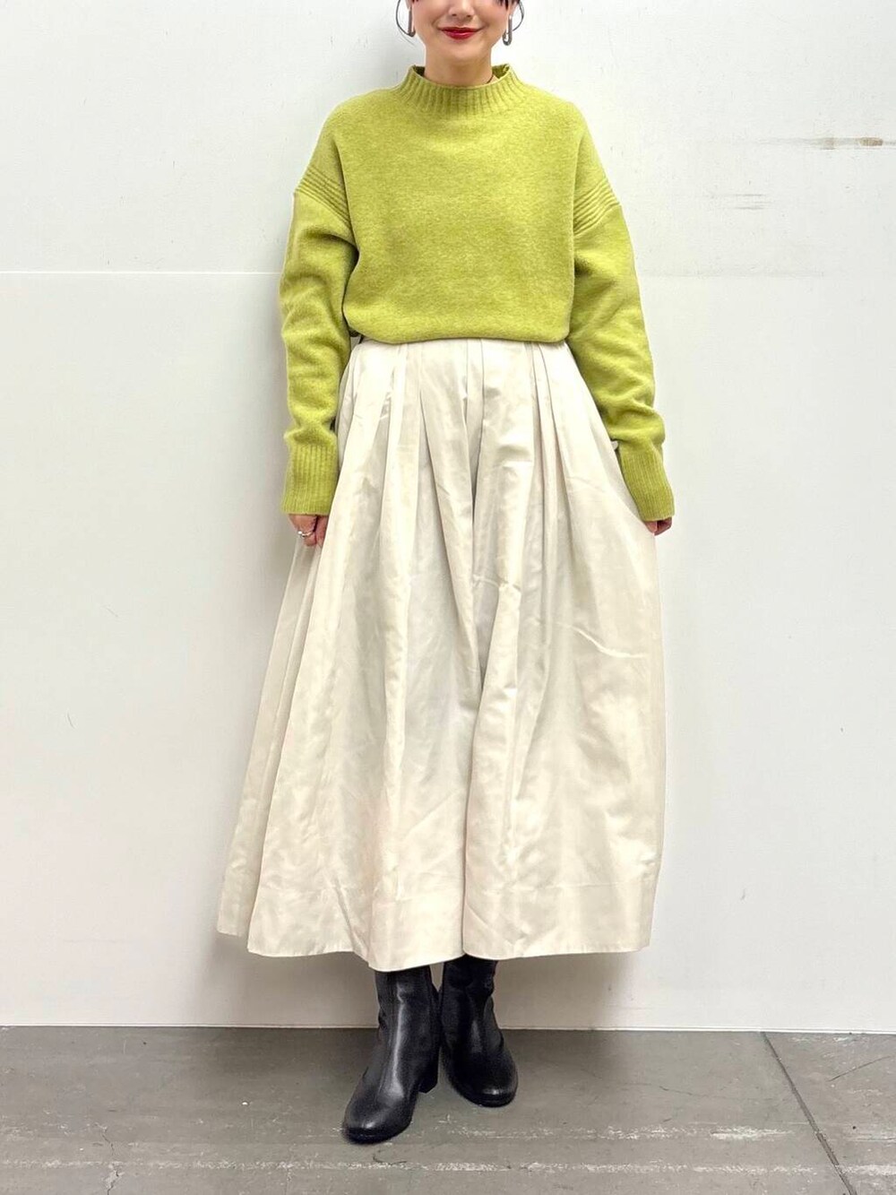 ブラック系のブーツ、ホワイト系のスカート、グリーン系のニット/セーターを着用したレディースの冬コーディネートの4枚目の写真