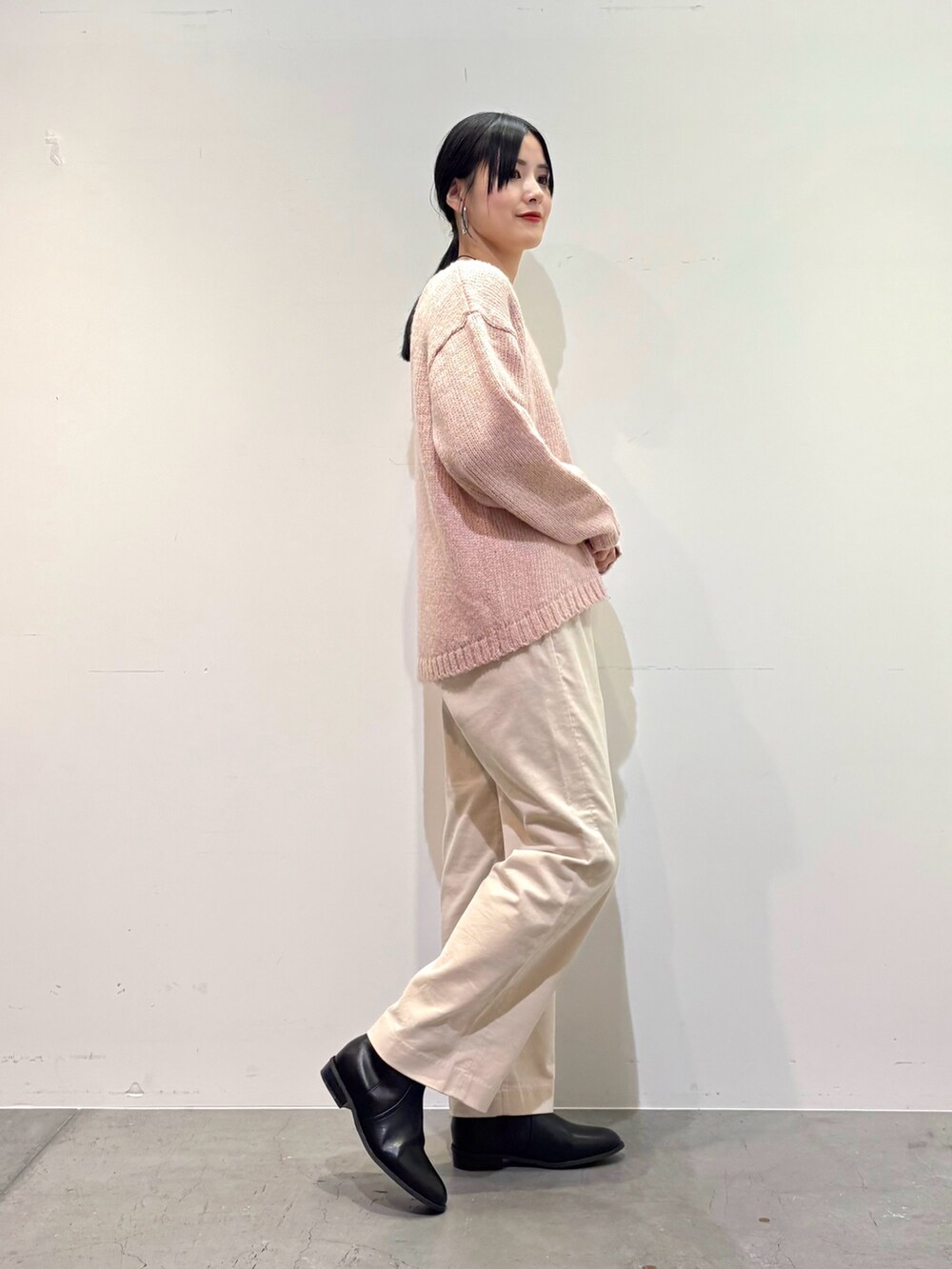 ピンク系のニット/セーター、ホワイト系のその他パンツ、ブラック系のブーツを着用したレディースの冬コーディネートの2枚目の写真