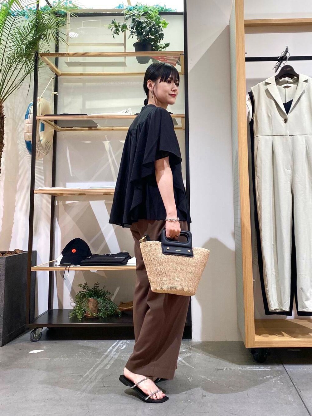 ベージュ系のハンドバッグ、ブラック系のサンダル、ブラック系のシャツ/ブラウスを着用したレディースの夏コーディネートの3枚目の写真