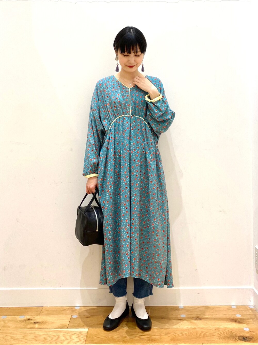 ホワイト系のチェスターコート、グリーン系のワンピース、ブルー系のデニムパンツを着用したレディースの冬コーディネートの2枚目の写真