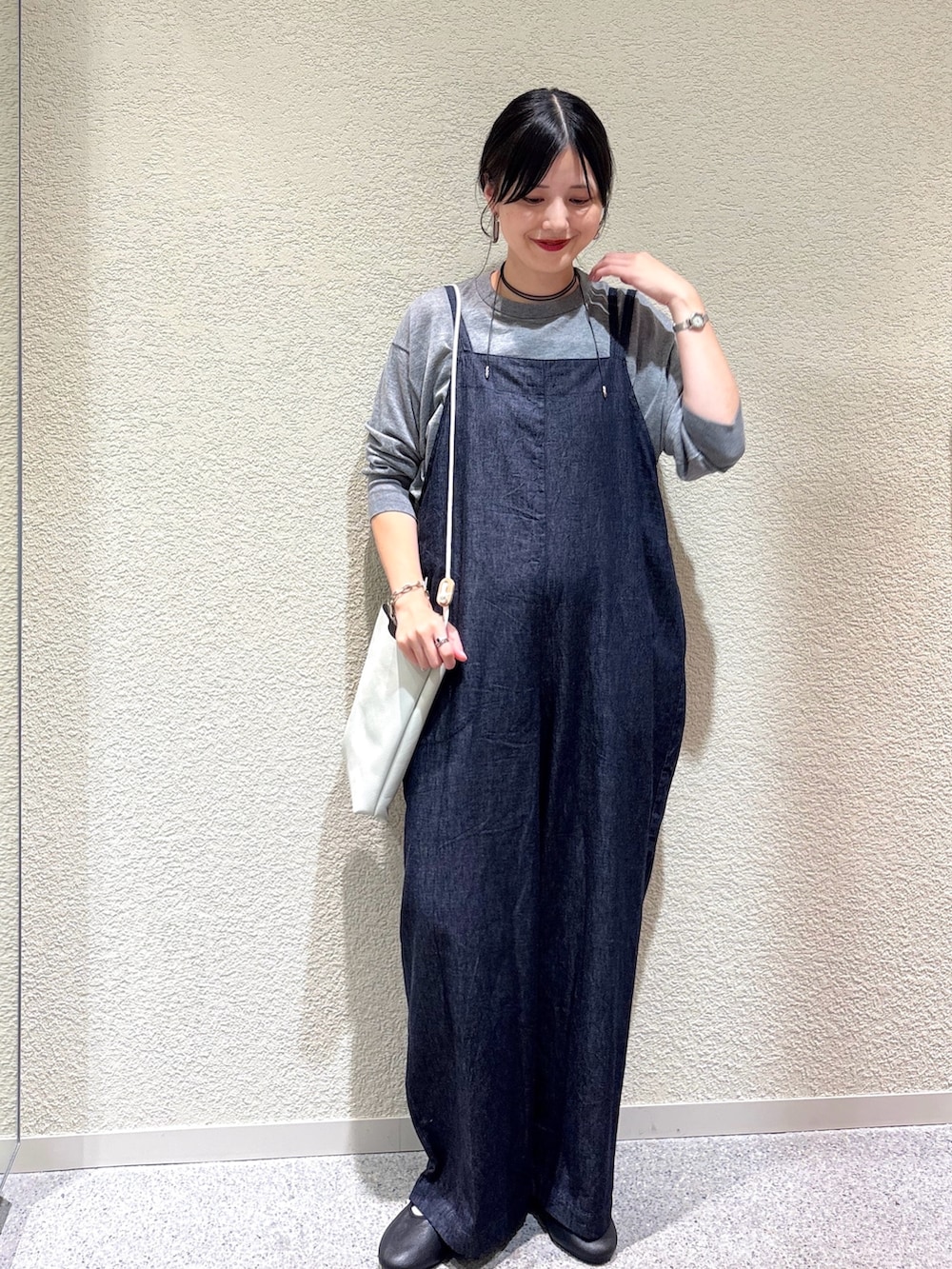 グレー系のニット/セーター、ブルー系のサロペット/オーバーオール、ホワイト系のショルダーバッグを着用したレディースの秋コーディネートの6枚目の写真