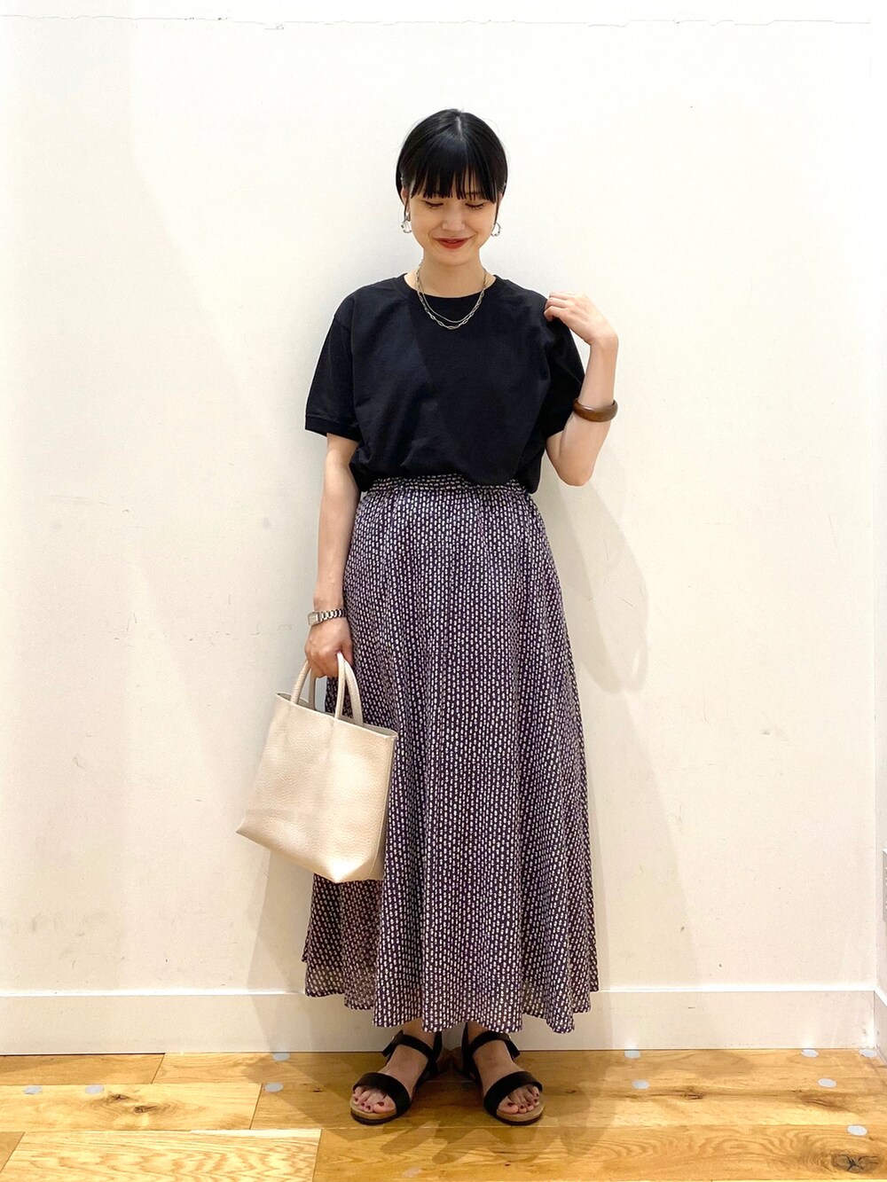 ブラック系のTシャツ/カットソー、グレー系のスカート、ホワイト系のトートバッグを着用したレディースの夏コーディネートの2枚目の写真
