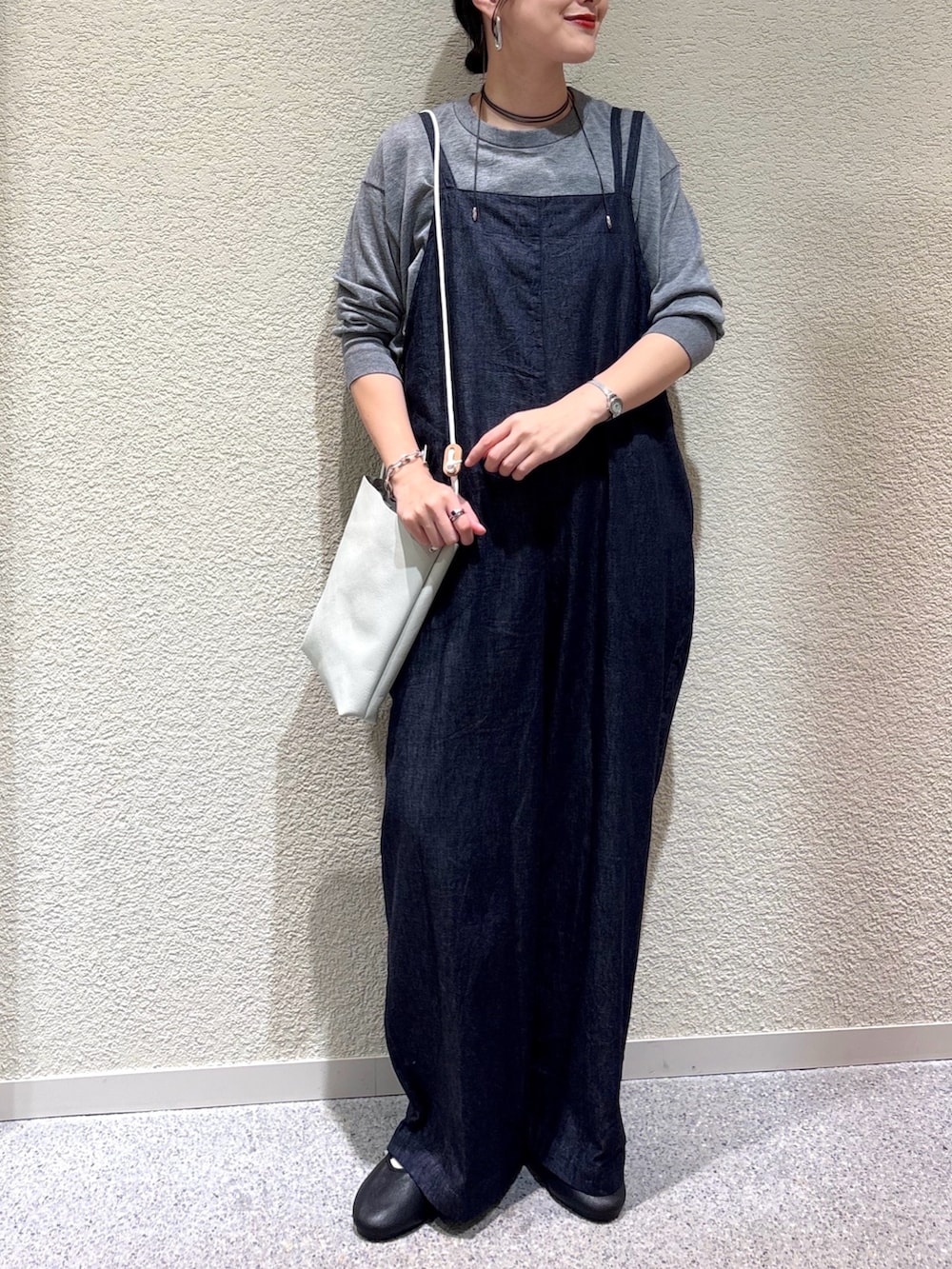 グレー系のニット/セーター、ブルー系のサロペット/オーバーオール、ホワイト系のショルダーバッグを着用したレディースの秋コーディネートの4枚目の写真