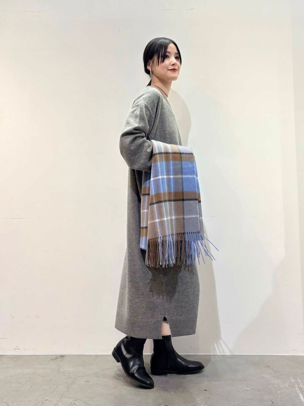 ブラック系のダウンジャケット/コート、ブラック系のブーツ、グレー系のワンピースを着用したレディースの冬コーディネートの5枚目の写真