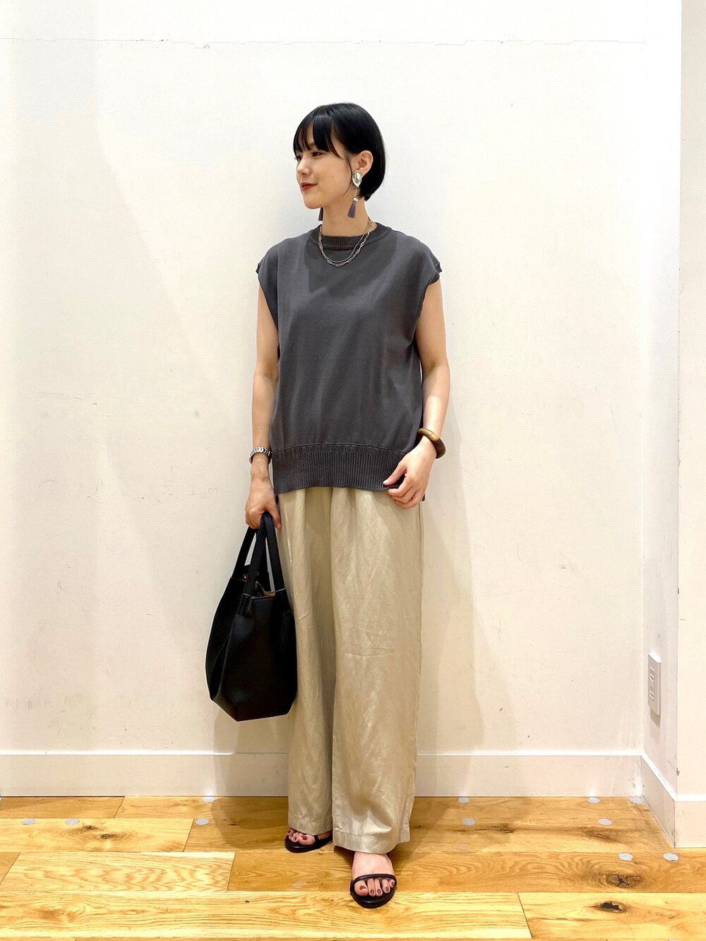 グレー系のニット/セーター、ベージュ系のその他パンツ、ブラック系のトートバッグを着用したレディースの夏コーディネートの2枚目の写真