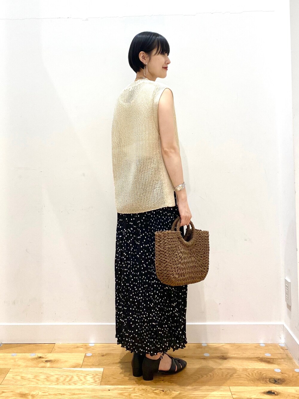 ベージュ系のベスト、ホワイト系のタンクトップ、ブラック系のスカートを着用したレディースの春コーディネートの3枚目の写真