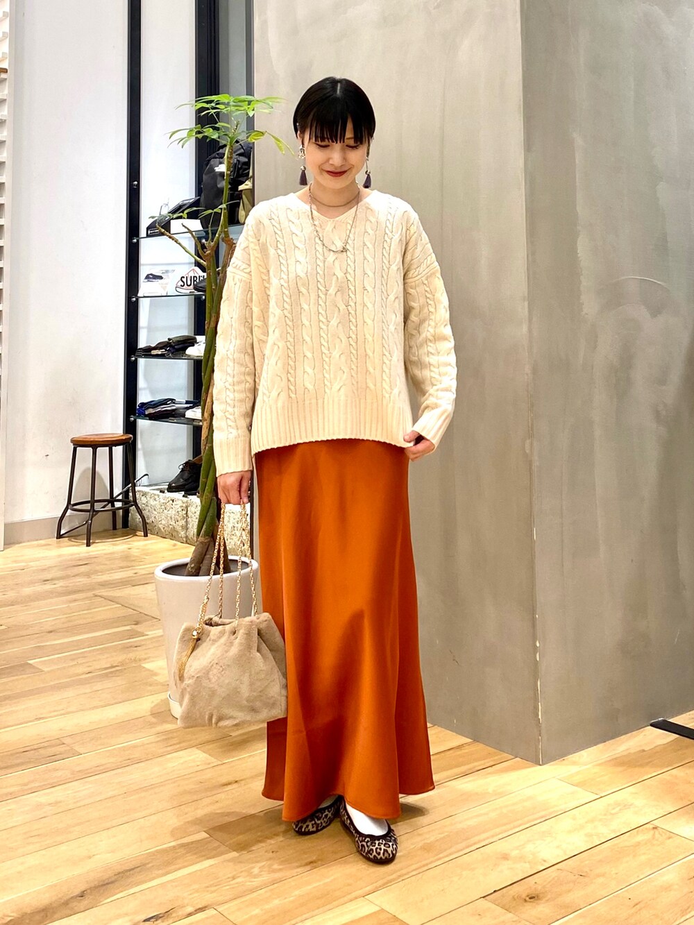 ホワイト系のダウンジャケット/コート、ホワイト系のニット/セーター、オレンジ系のスカートを着用したレディースの冬コーディネートの3枚目の写真