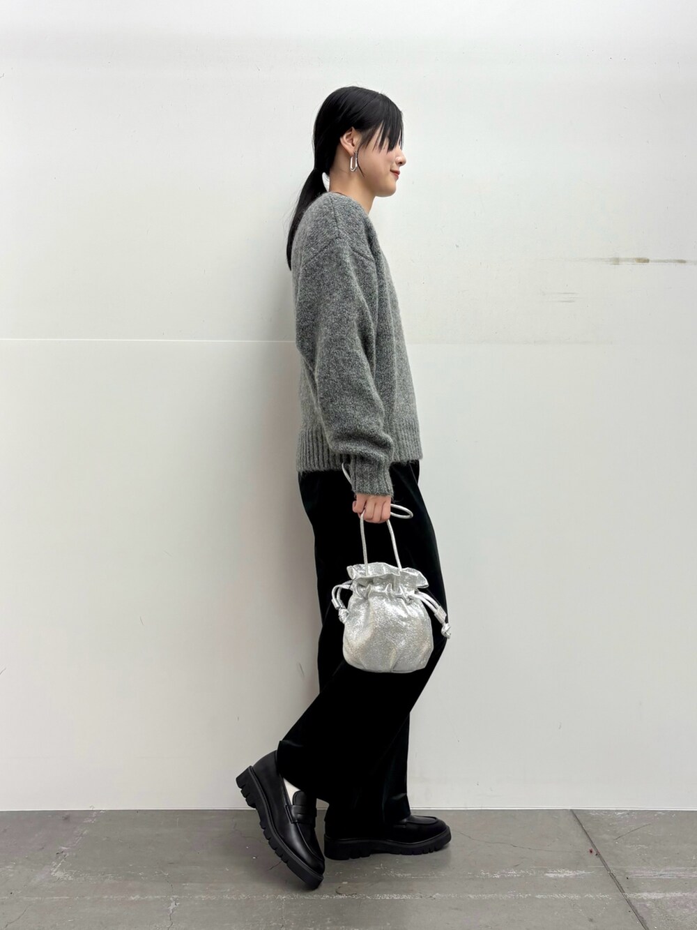グレー系のニット/セーター、ブラック系のその他パンツ、シルバー系のショルダーバッグを着用したレディースの冬コーディネートの2枚目の写真